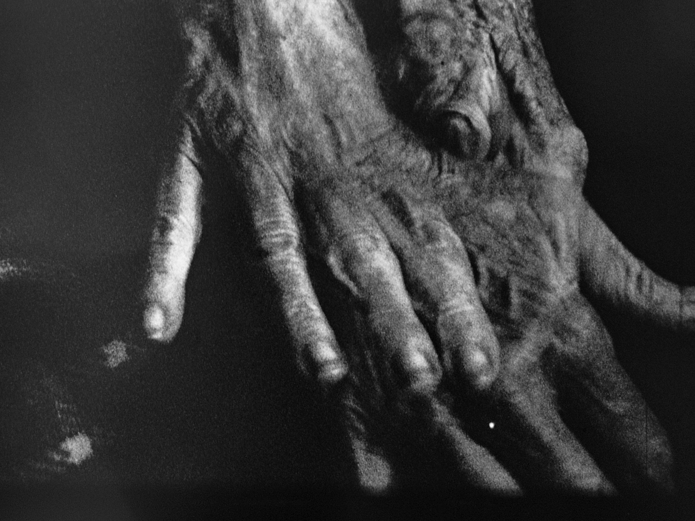 Black and white close up of two pairs of hands resting together.