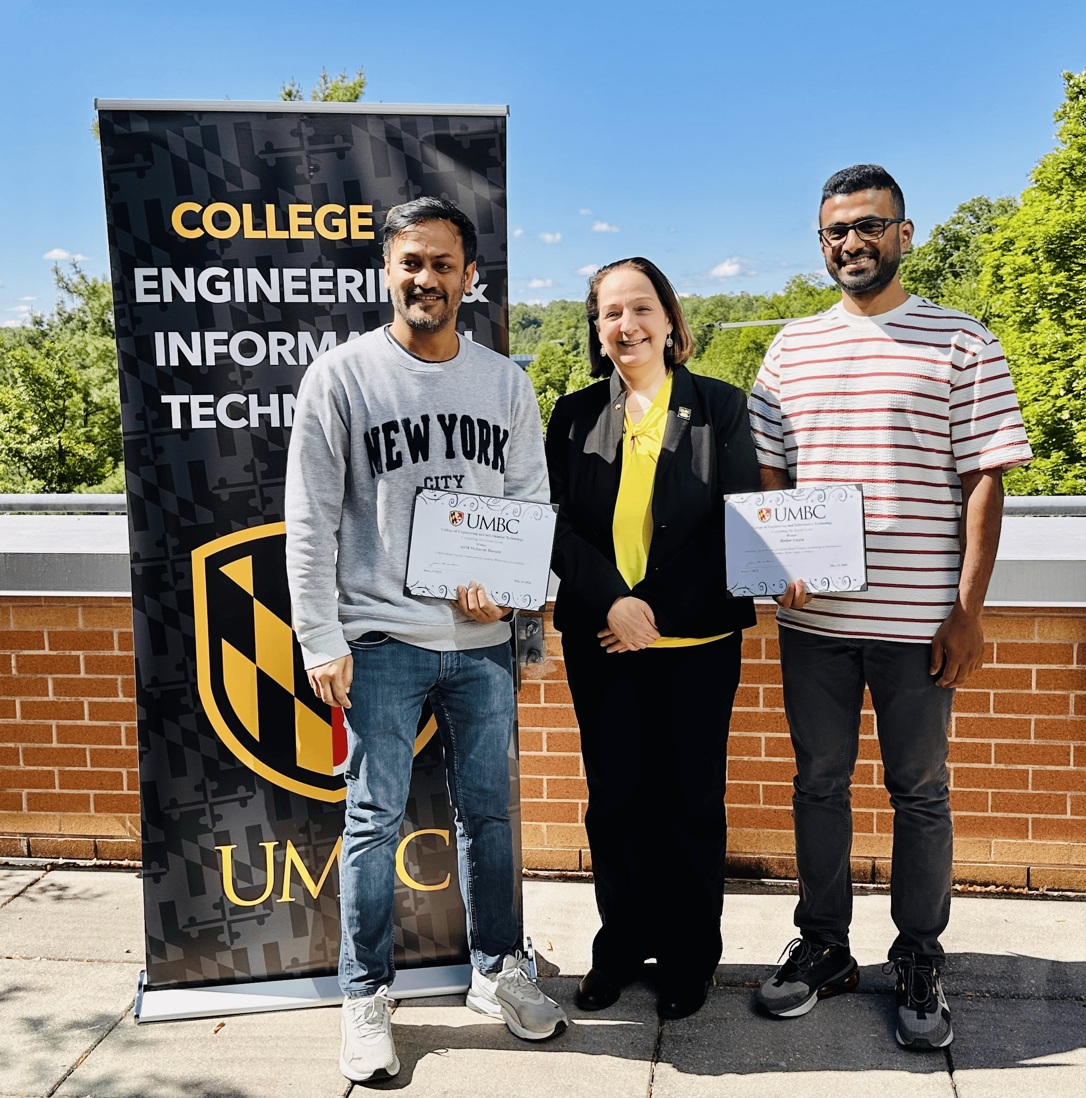 Rishav Gupta and ASM Mobarak Hossain receiving the COEIT Computing for Social Good Award from Jeanne M. van Briesen, dean of the College of Engineering and Information Technology.
