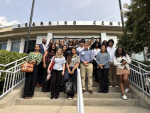 A group of students stands together on stairs outside a campus building.