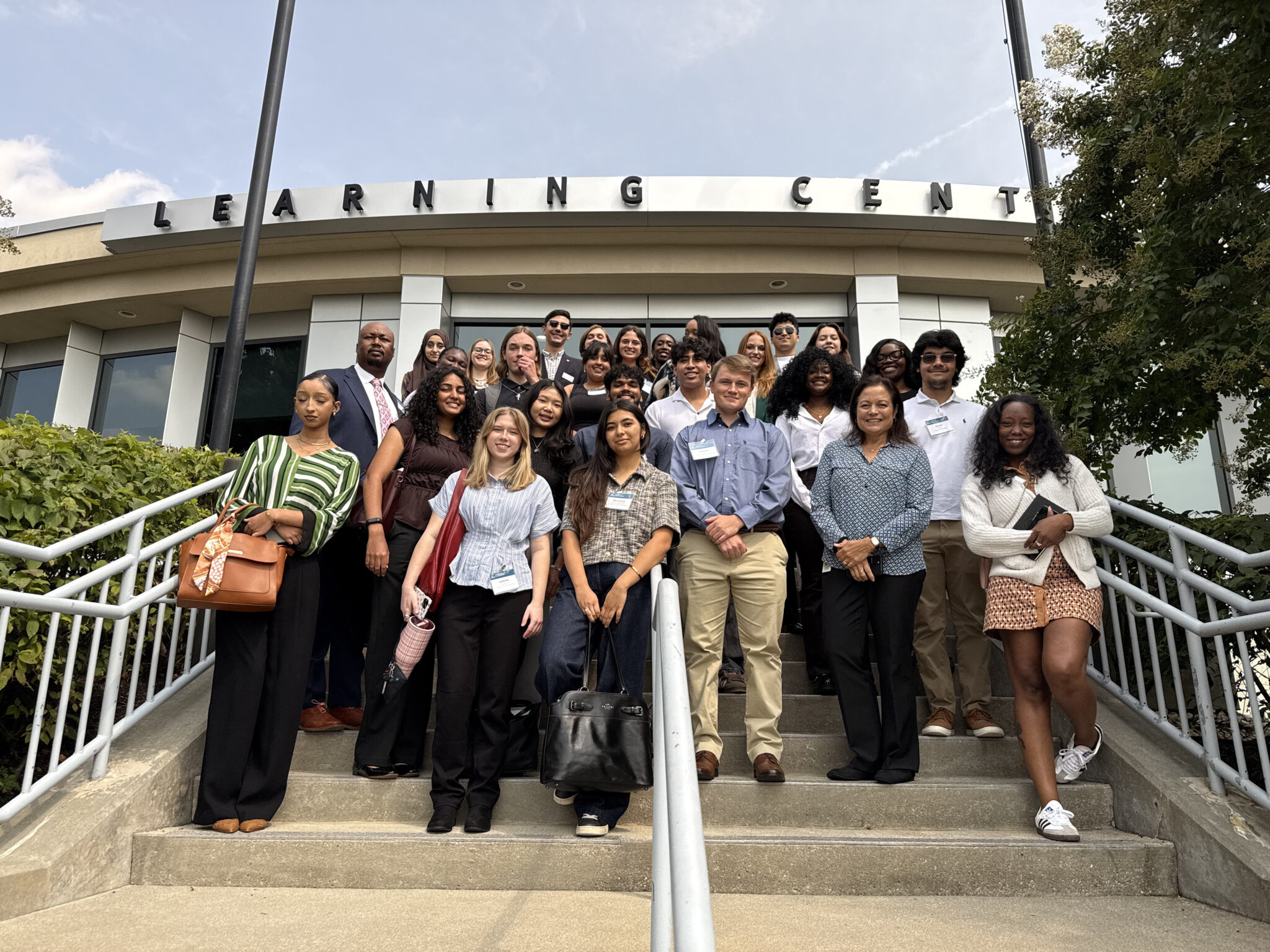 A group of students stands together on stairs outside a campus building.