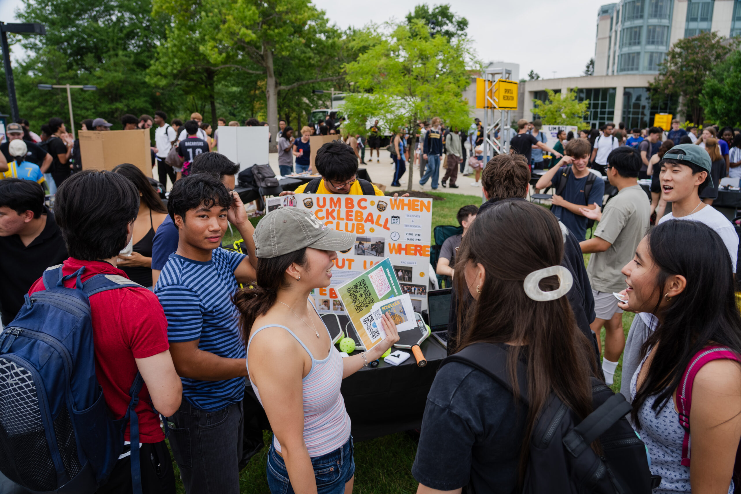 Thousands of students walk around tables set up on a side walk looking at information about student clubs at iFest